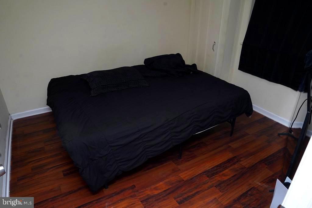 3814 Erdman Avenue Baltimore, MD 21213 - Photo 15 of 18 a bedroom with a bed chair and wooden floor