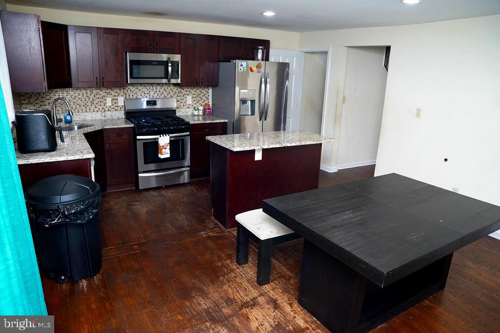 3814 Erdman Avenue Baltimore, MD 21213 - Photo 6 of 18 a kitchen with stainless steel appliances kitchen island granite countertop a refrigerator a stove top oven a sink and dishwasher