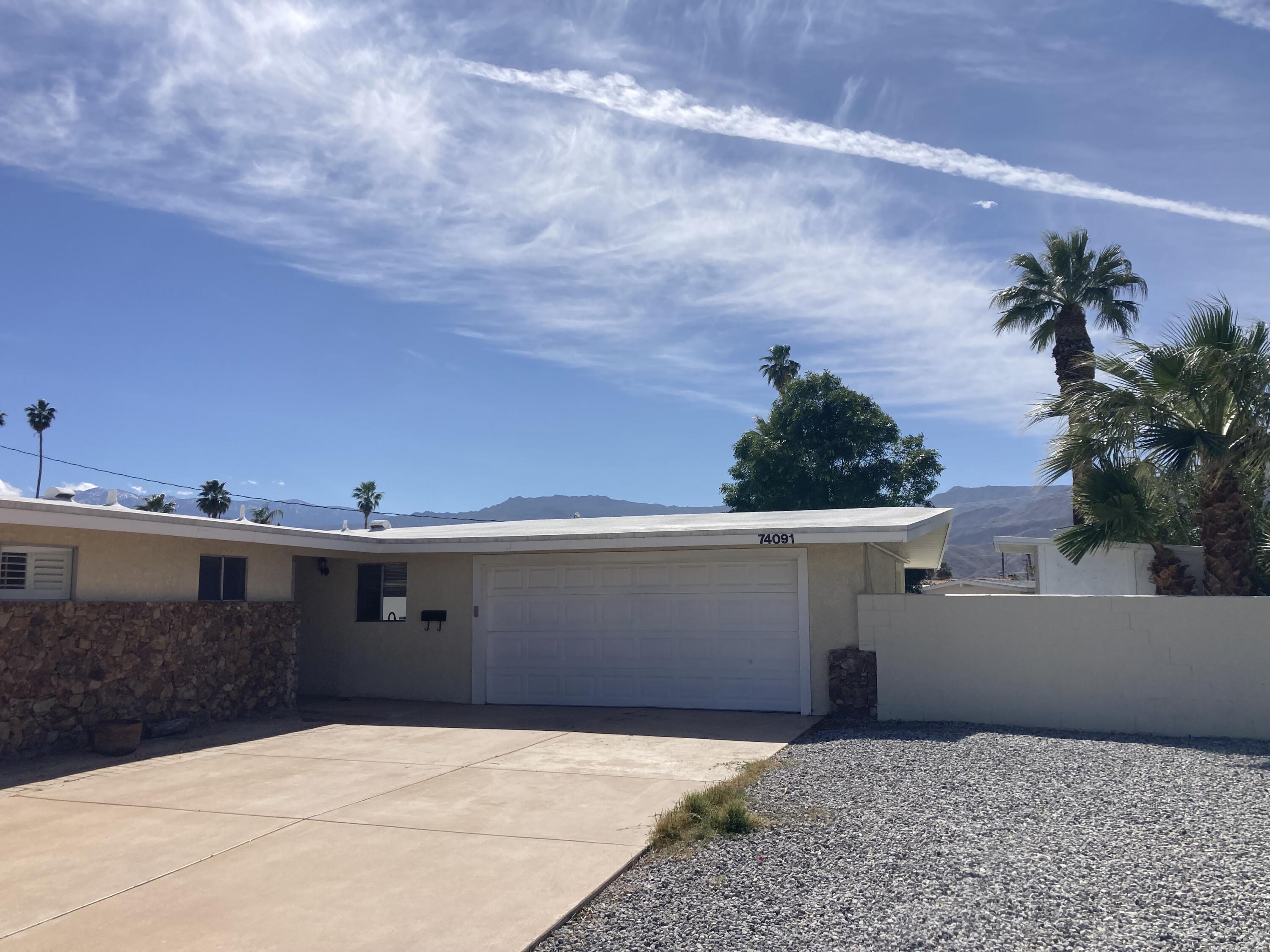 74091 Aster Drive Palm Desert, CA 92260 - Photo 14 of 16 a view of a white house with a yard and potted plants