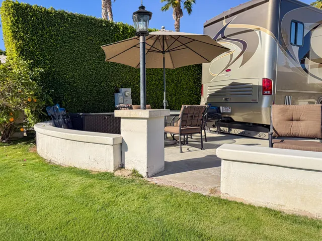 a view of a patio with couches table and chairs under an umbrella