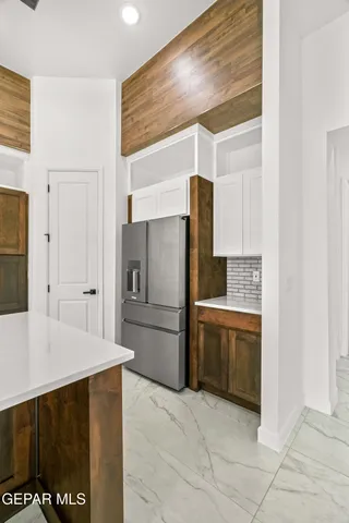 a large kitchen with a large counter top space a sink stainless steel appliances and cabinets