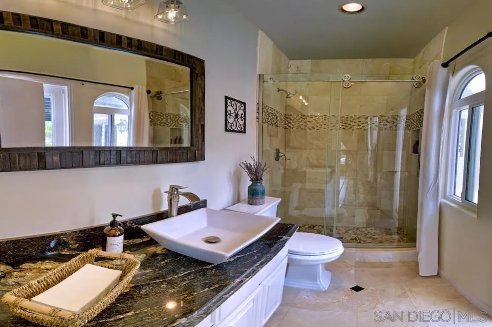 17843 Valle Verde Road Poway, CA 92064 - Photo 54 of 70 a bathroom with a granite countertop sink toilet a mirror a vanity and shower