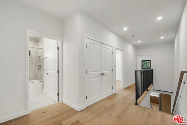 a view of a hallway with wooden floor and bathroom