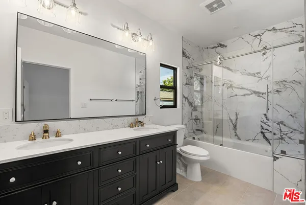 a bathroom with a double vanity sink toilet mirror and bathtub