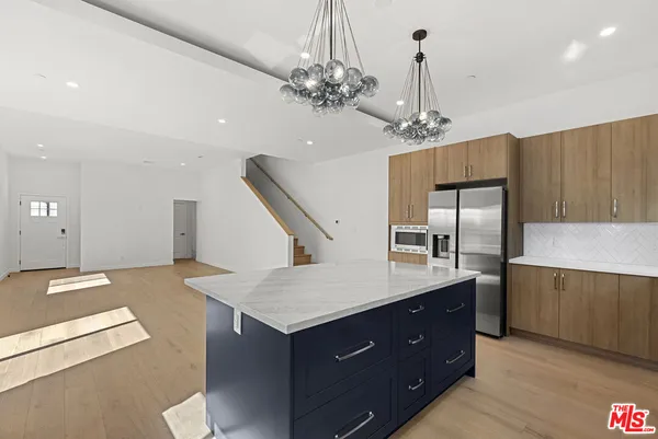 a kitchen with stainless steel appliances granite countertop a kitchen island a stove and a refrigerator