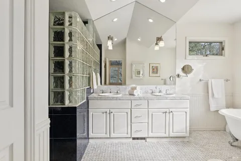 a spacious bathroom with a double vanity sink a toilet a mirror and shower