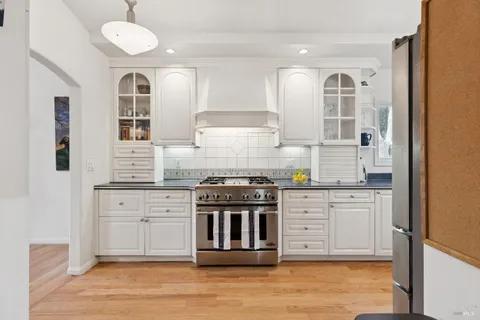 a kitchen with stainless steel appliances granite countertop a stove and white cabinets