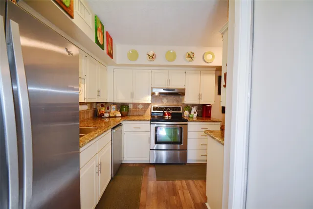 a kitchen with stainless steel appliances granite countertop a refrigerator and a stove