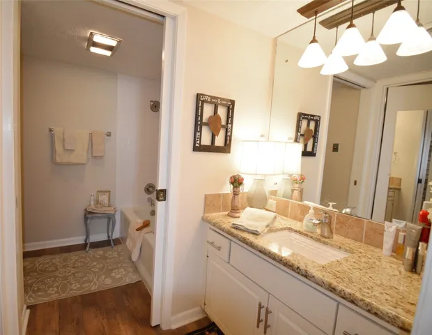 a bathroom with a granite countertop sink a light fixture and a mirror