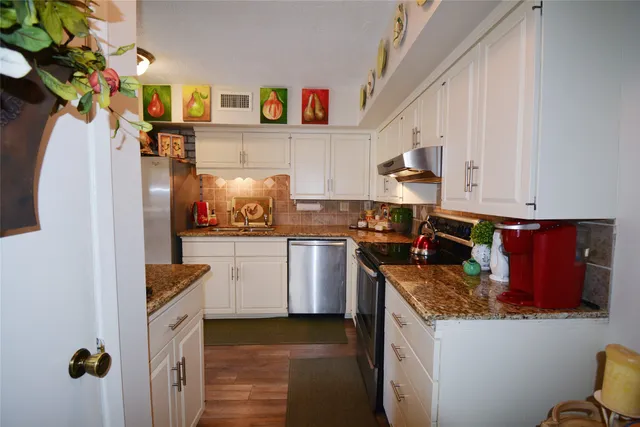 a kitchen with stainless steel appliances granite countertop a stove a sink and a refrigerator