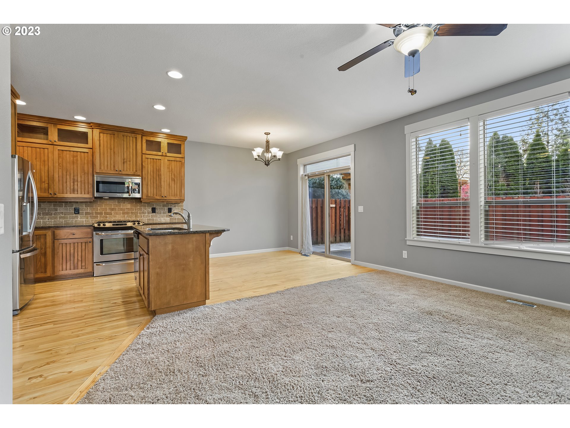 2267 Southwest 184th Terrace Beaverton, OR 97003 - Photo 10 of 39 a kitchen with stainless steel appliances kitchen island granite countertop a stove top oven a sink a dining table and chairs with wooden floor