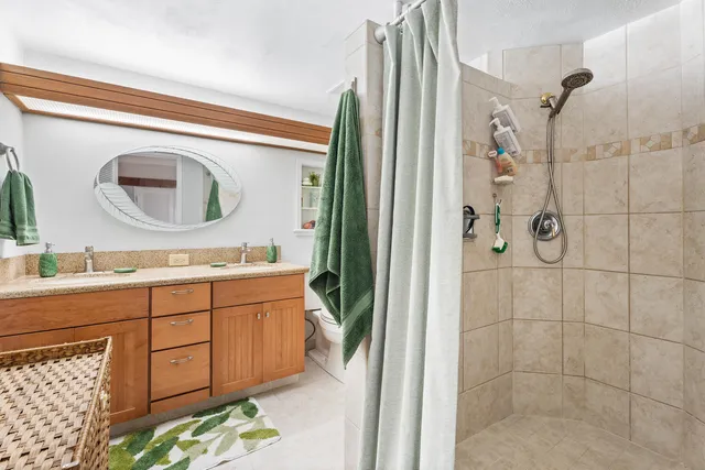 a bathroom with a granite countertop sink a mirror and shower