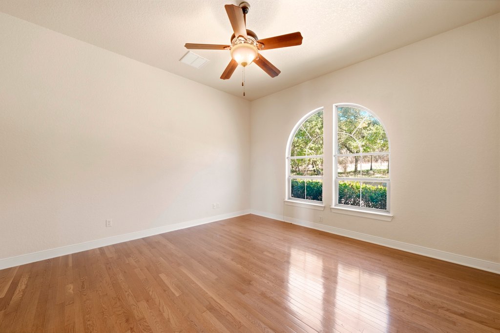 143 Champion Way Spring Branch, TX 78070 - Photo 25 of 40 an empty room with wooden floor chandelier fan and windows