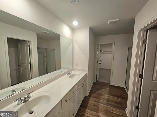 a bathroom with a double vanity sink and mirror with shower