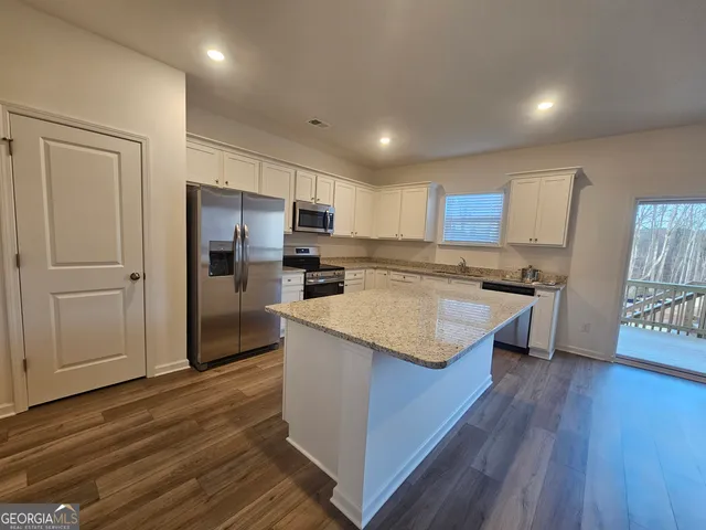a kitchen with kitchen island granite countertop wooden floors and stainless steel appliances