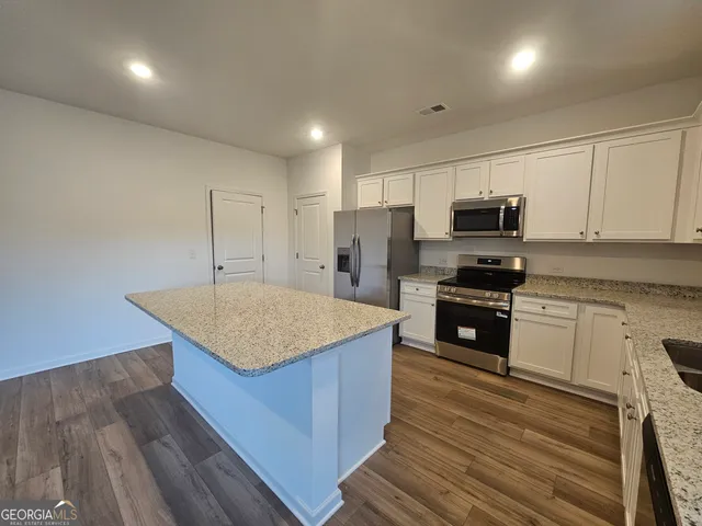 a kitchen with stainless steel appliances kitchen island granite countertop a stove a sink and a microwave