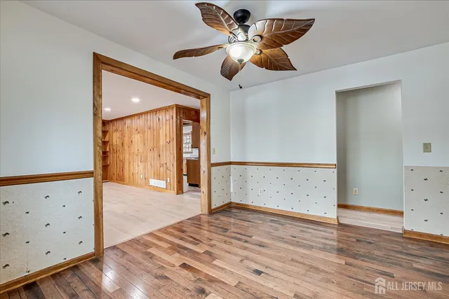 a view of empty room with wooden floor and fan