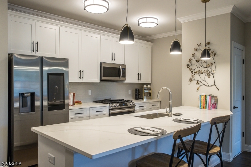 663 Springfield Avenue, Unit 53 Berkeley Heights, NJ 07922 - Photo 7 of 14 a kitchen with stainless steel appliances a table chairs and a refrigerator
