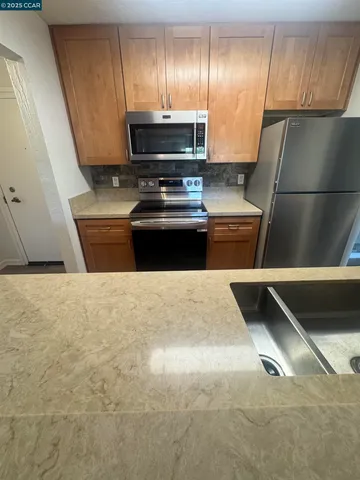 a kitchen with granite countertop a refrigerator and a stove top oven