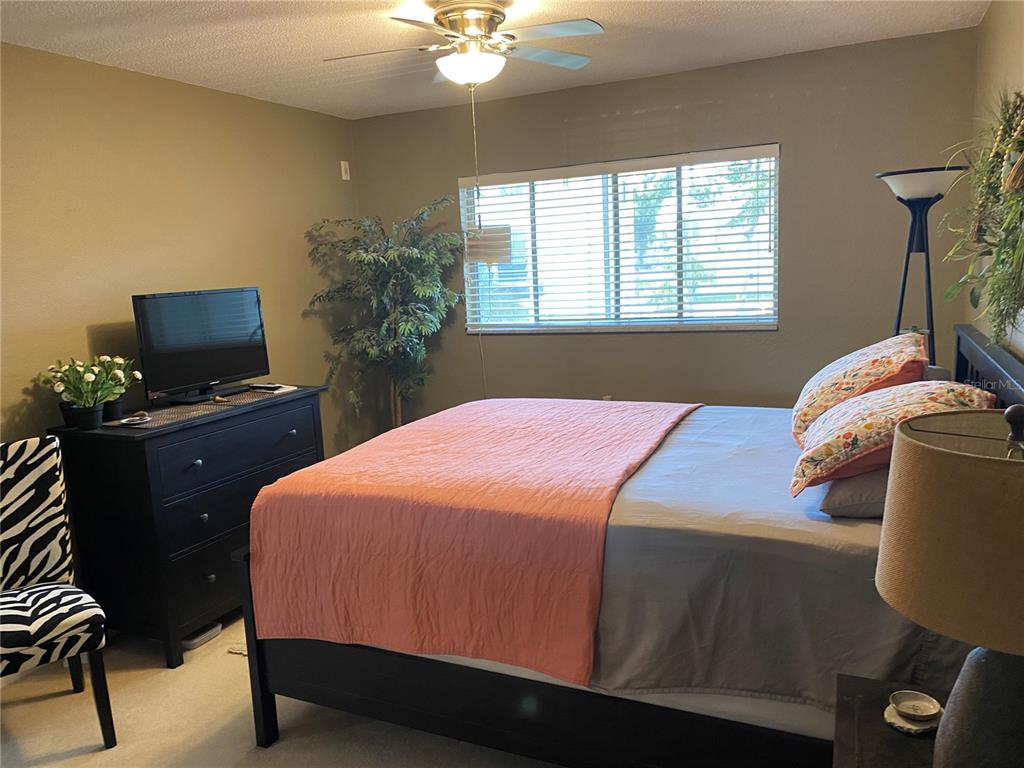 8455 112th Street North, Unit 212 Seminole, FL 33772 - Photo 8 of 21 a bedroom with a bed and a flat tv screen on dresser