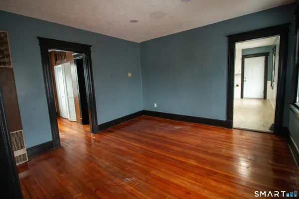 a view of empty room with wooden floor and fan