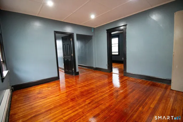 an empty room with wooden floor and mirror