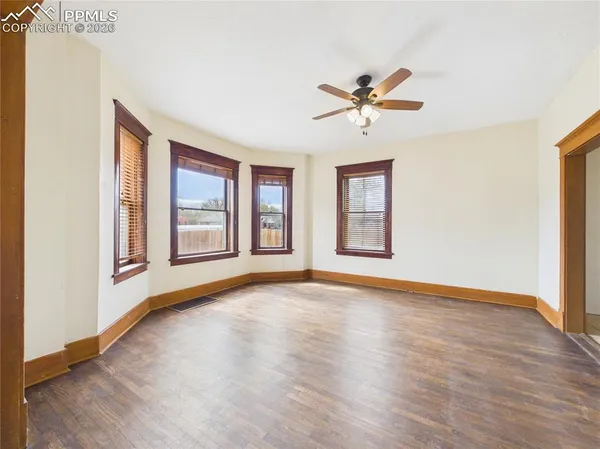 a view of an empty room with window and wooden floor