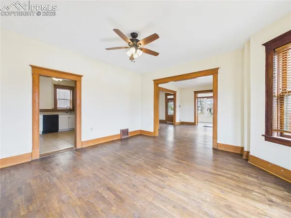 an empty room with wooden floor closet and windows
