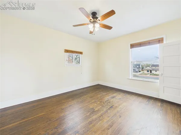 an empty room with wooden floor and ceiling fan