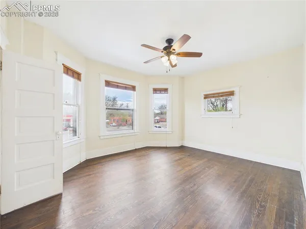 a view of empty room with wooden floor and fan