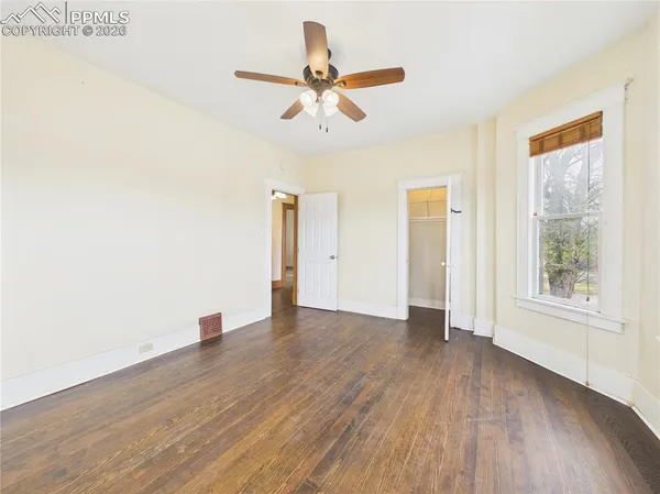 a view of an empty room with wooden floor and a window