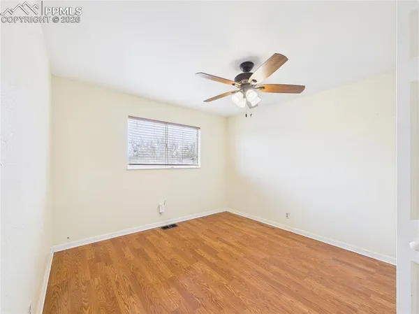 a view of a big room with wooden floor and a chandelier fan
