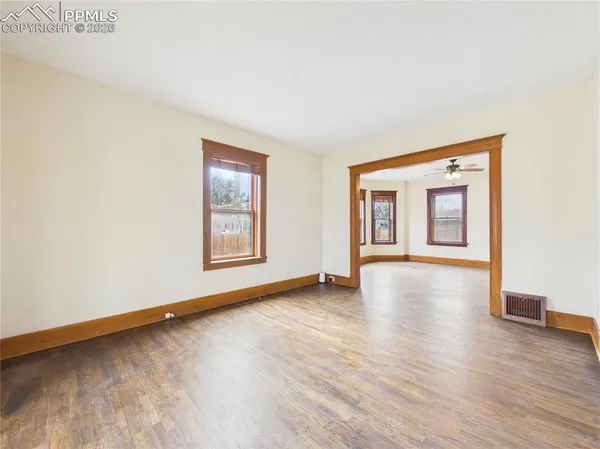 a view of an empty room with window and wooden floor
