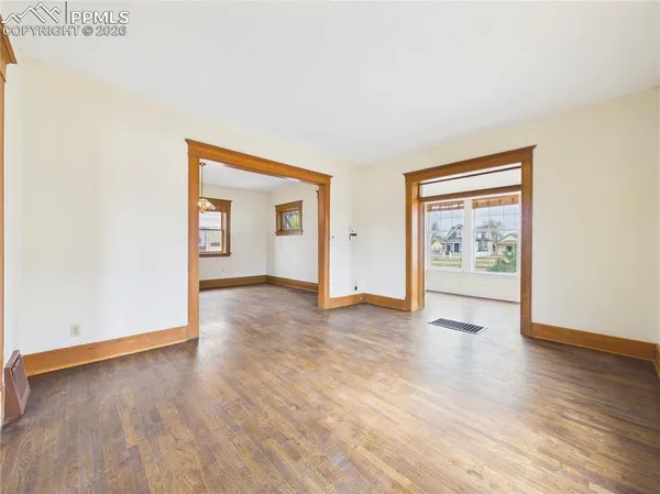an empty room with wooden floor and windows