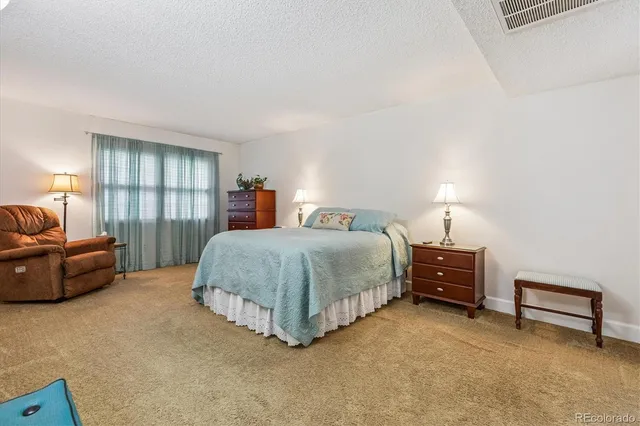 a spacious bedroom with a bed and a lamp