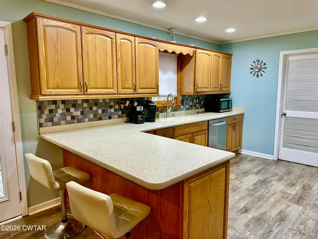 a view of kitchen island a sink wooden floor and living room