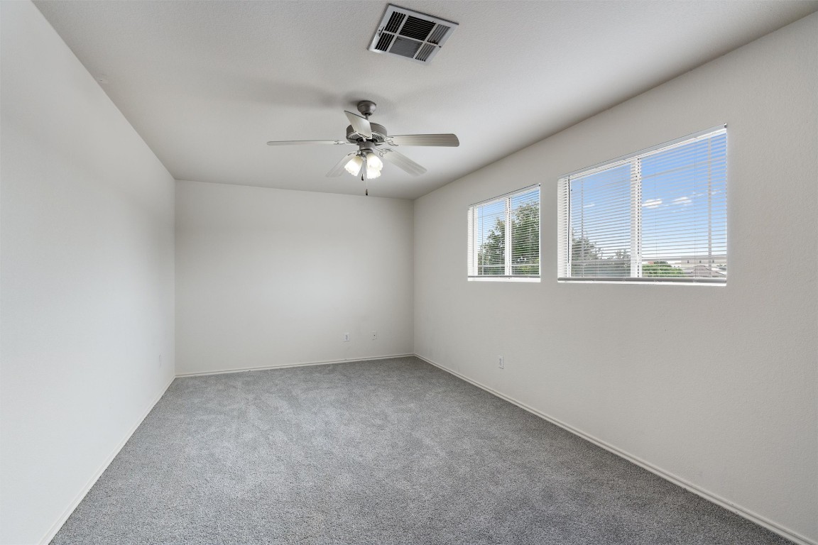 7432 Cayenne Lane Austin, TX 78741 - Photo 17 of 30 an empty room with a chandelier fan and windows