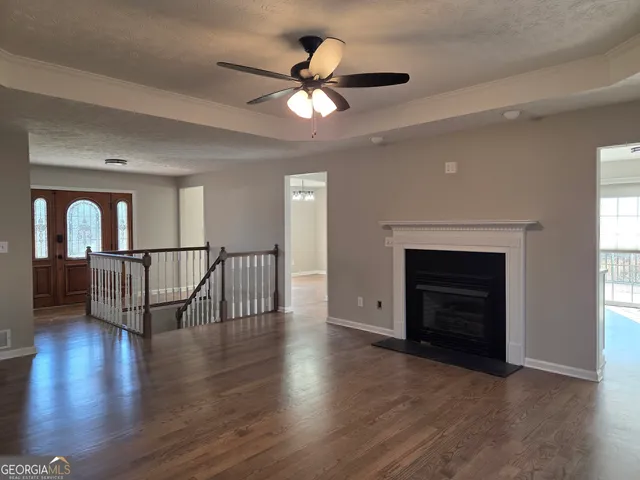 a view of an empty room with wooden floor a ceiling fan and a window