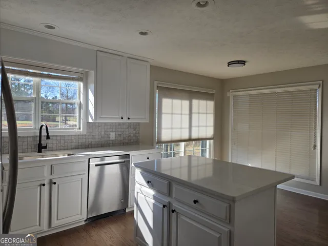 a kitchen with white cabinets sink and window