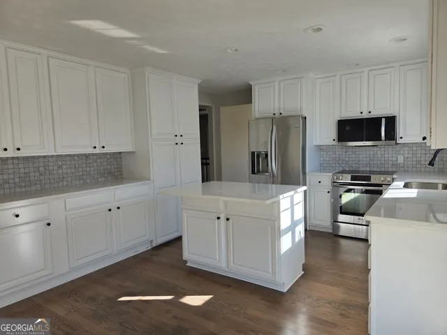a kitchen with stainless steel appliances white cabinets sink and wooden floor