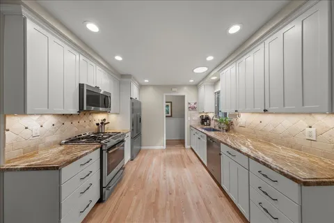 a large kitchen with stainless steel appliances granite countertop a lot of counter space and wooden floors