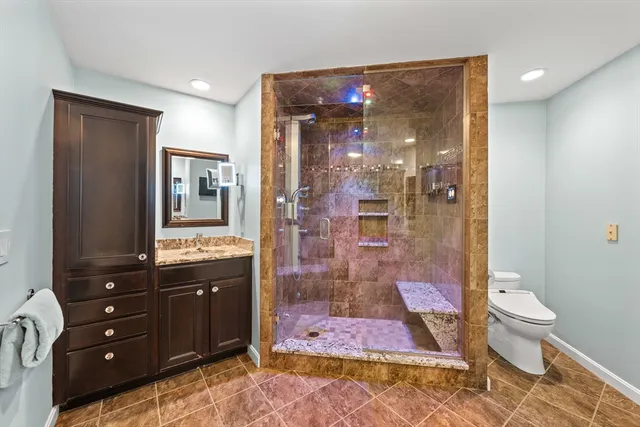 a bathroom with a granite countertop sink a toilet a mirror and shower