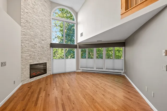 an empty room with wooden floor a fireplace and windows
