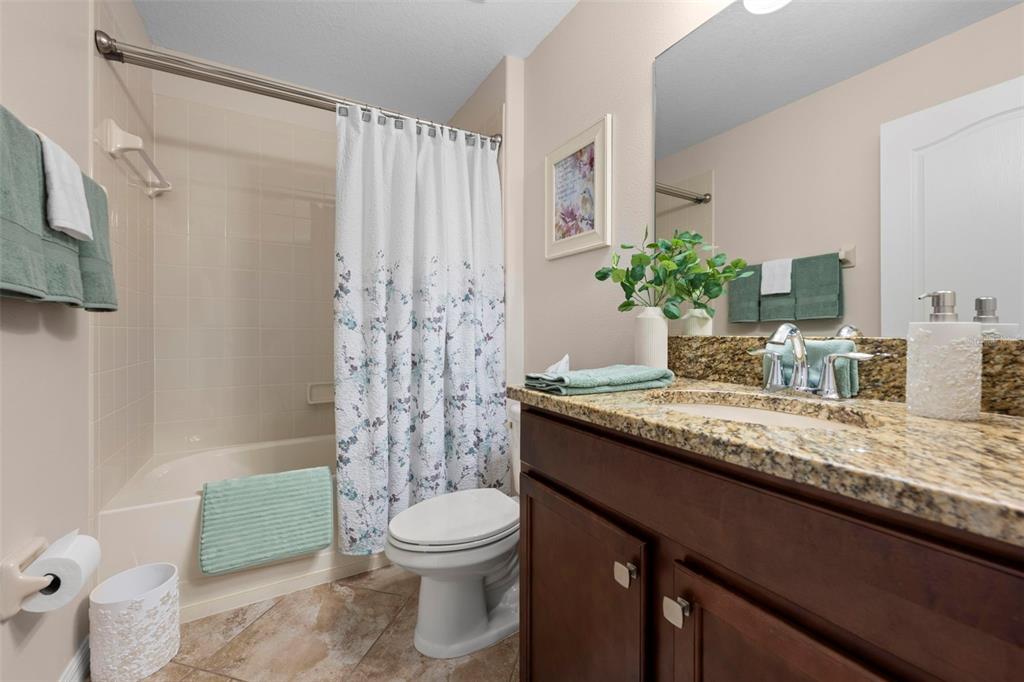 10114 Ives Loop Hudson, FL 34667 - Photo 37 of 49 a bathroom with a granite countertop sink a toilet and tub