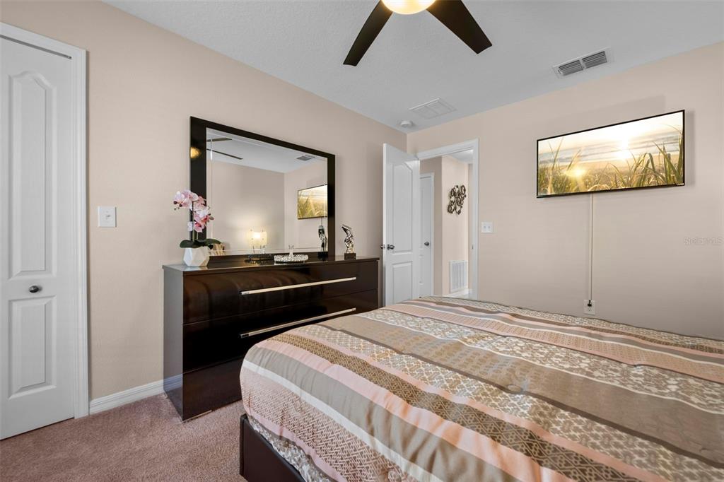 10114 Ives Loop Hudson, FL 34667 - Photo 40 of 49 a bedroom with a bed and a flat tv screen on dresser