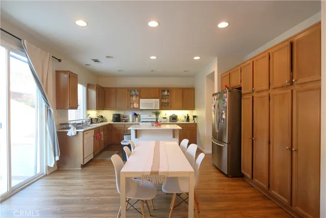 a kitchen with stainless steel appliances granite countertop a refrigerator a sink dishwasher a stove and a refrigerator with wooden floor