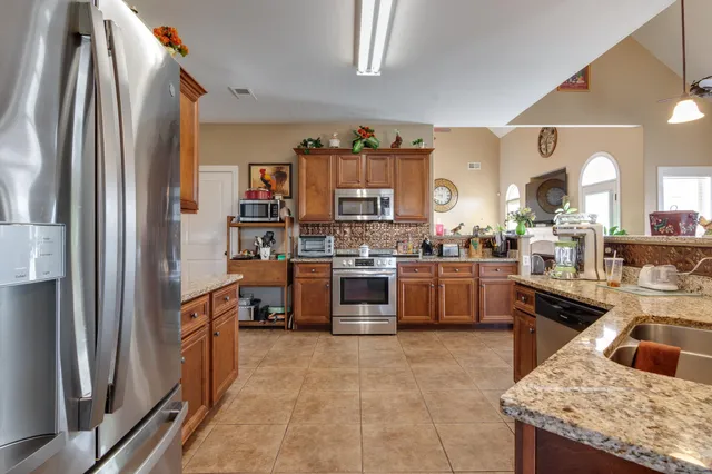 a kitchen with stainless steel appliances granite countertop a refrigerator a stove and a sink