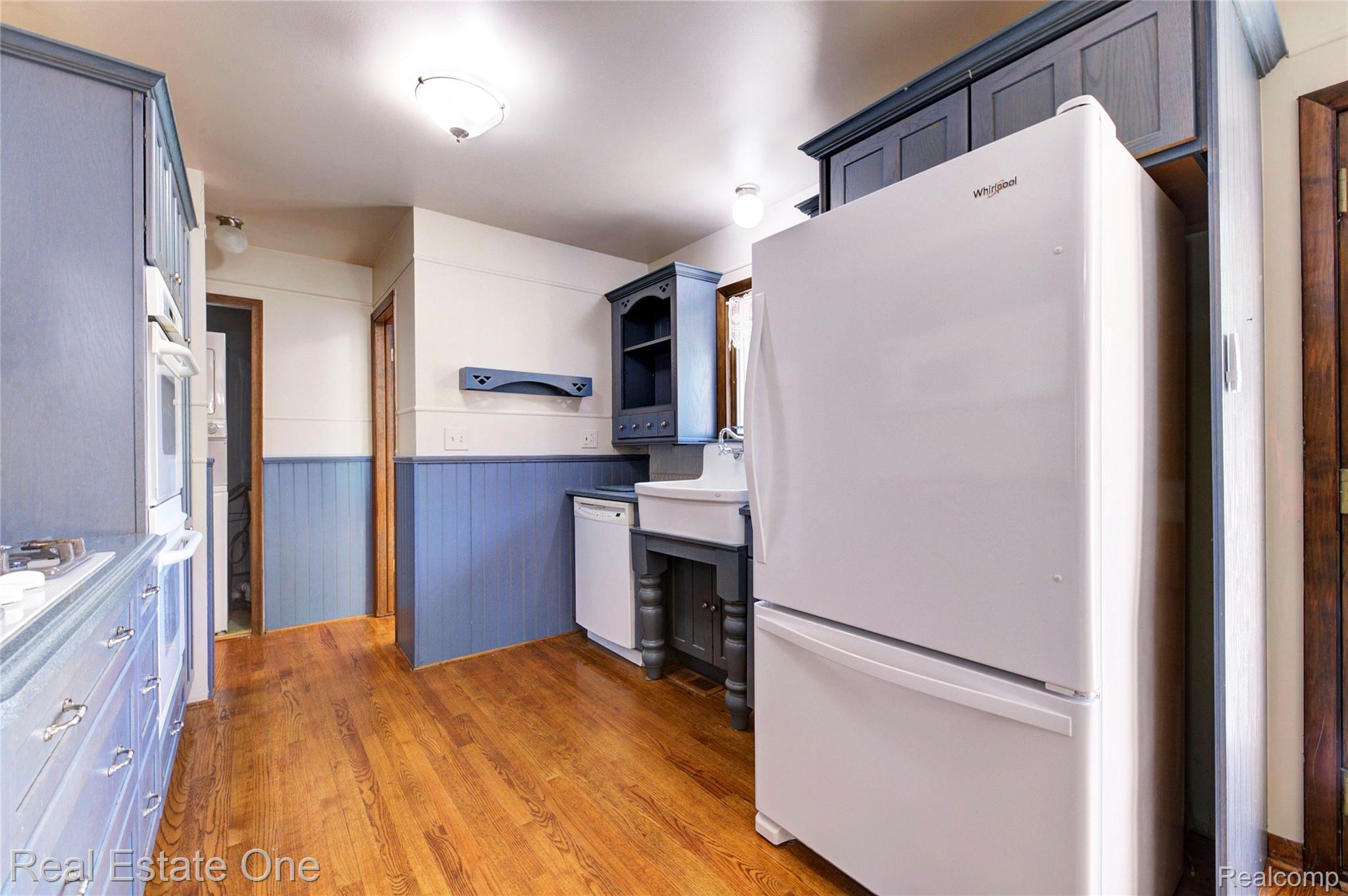 3125 West Commerce Road Milford, MI 48380 - Photo 15 of 63 Kitchen featuring wood-finish flooring, blue painted cabinetry, white appliances, wainscoting, and recessed lighting