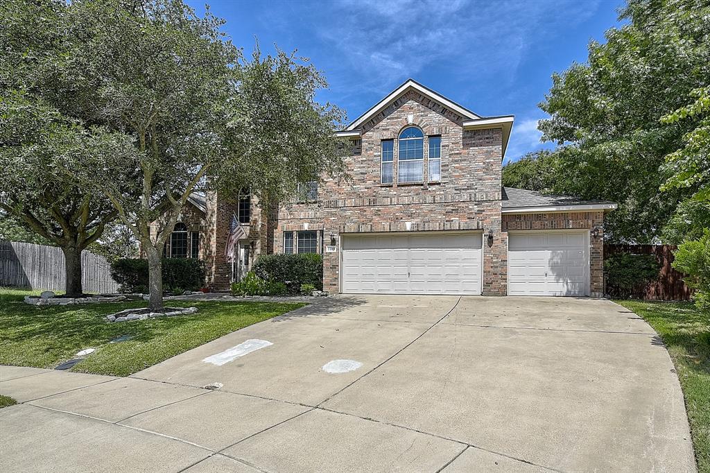 Traditional-style house featuring driveway, an attached garage, stone siding, and brick siding