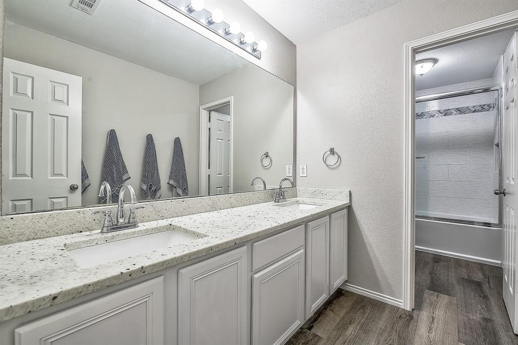 1109 Brandy Court Midlothian, TX 76065 - Photo 16 of 26 Bathroom with double vanity, dark wood-style flooring, a textured wall, combined bath / shower with glass door, and a textured ceiling